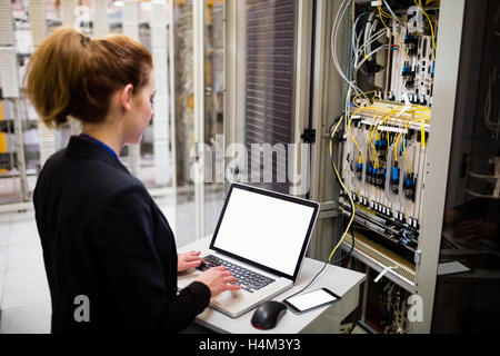 Technician using laptop while analyzing server Stock Photo