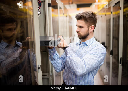 Technician removing server from rack mounted server Stock Photo