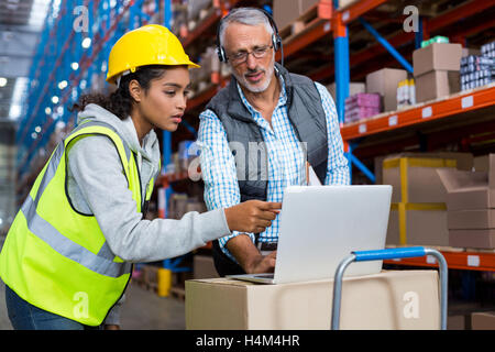 Warehouse manager and female worker using laptop Stock Photo