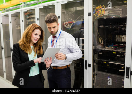 Technicians using digital tablet while analyzing server Stock Photo