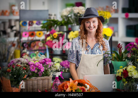 Smiling florist using laptop in flower shop Stock Photo