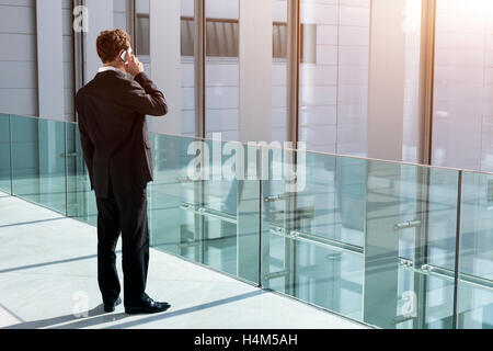 Businessman taking a call on smartphone in office building Stock Photo