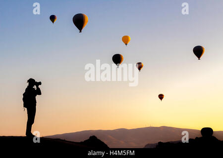 Female tourist taking photos of hot air balloon in Cappadocia, Anatolia, Turkey Stock Photo