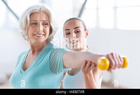 Optimistic cheerful woman exercising with a coach Stock Photo