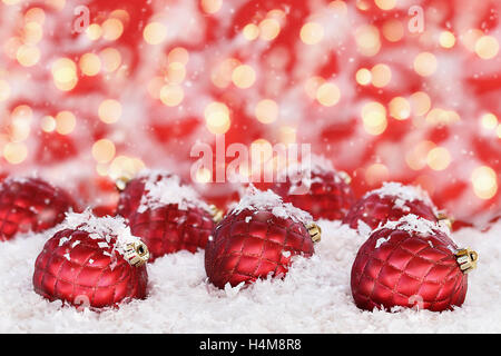 Beautiful ornate glass Christmas ornaments with falling snowflakes against a red and gold bokeh background. Stock Photo