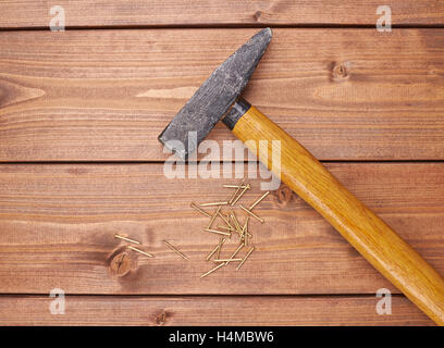 Big hammer with pile of metal nails on wooden surface Stock Photo