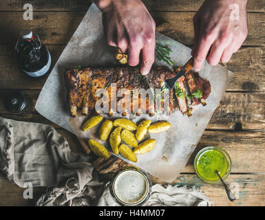 Man' s hands holding cutlery, cutting pork ribs into pieces Stock Photo