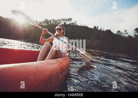 Young woman canoing in a lake. Woman paddling kayak on a summer day. Stock Photo