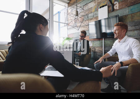 Young man sitting in discussing business with colleagues. Business professionals in meeting room. Stock Photo