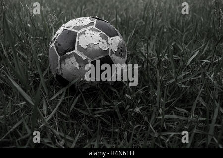 Old soccer ball on field Stock Photo