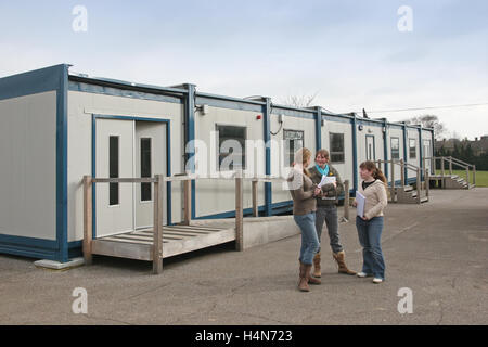 Sixth Form pupils chat outside a temporary, modular classroom block at a secondary school in Norfolk, UK Stock Photo