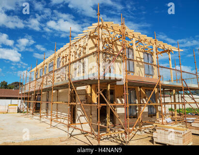 Construction site with the house in scaffolding against a blue sky Stock Photo