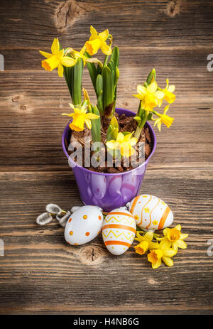 Spring flowers and easter eggs on rustic wooden table Stock Photo