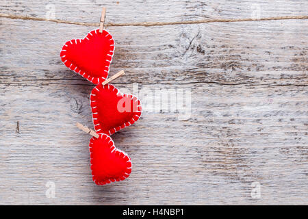 Three love hearts hanging on wooden texture background Stock Photo