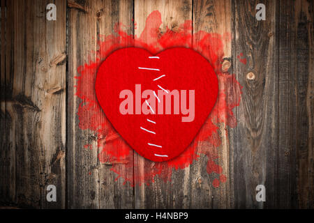 Broken heart stitched together on old wooden background Stock Photo