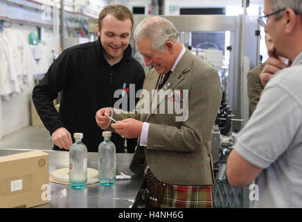 The Prince of Wales, known as the Lord of the Isles while in the Western Isles, puts a the label on a bottle of gin during a visit to the Isle of Harris Distillery, which he officially opened in Tarbert on the Isle of Harris. Stock Photo