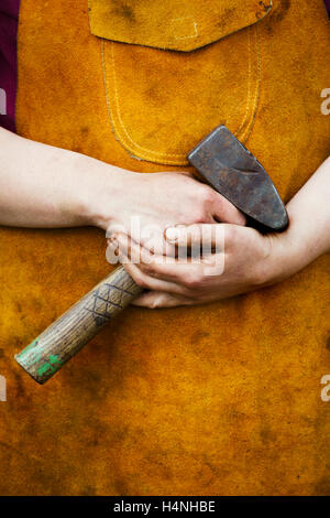 A man in a heatproof apron holding a mallet. Stock Photo
