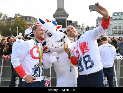 Mohamed Sbihi (right) and Alex Gregory take a picture with the Team GB mascot during the Olympic and Paralympic athletes heroes' return in London. Stock Photo