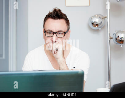 Man sitting at a desk in office using a laptop. Stock Photo
