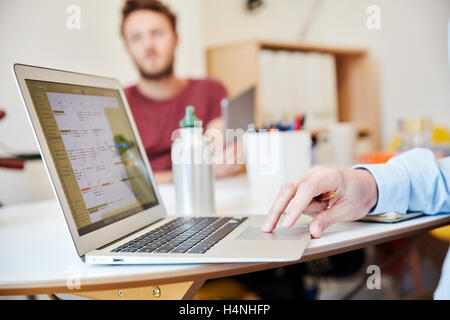 A man using a laptop and a man holding a digital tablet, working in office. Stock Photo