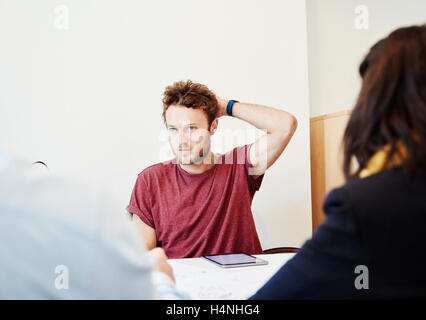 A man sitting in a meeting with two colleagues. Stock Photo