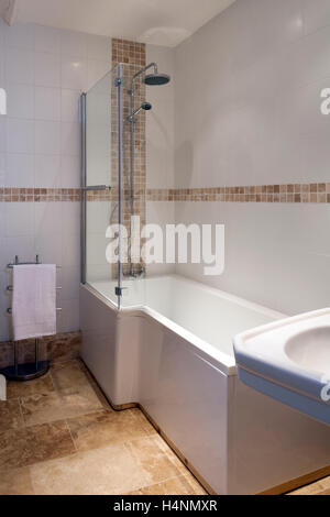 A contemporary tiled bathroom bath with shower over Stock Photo