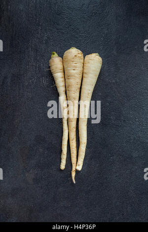 Three parsley roots on gray slate Stock Photo
