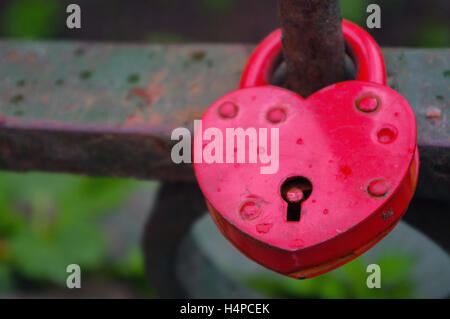 Red Padlock in heart style on the fence of a bridge Stock Photo