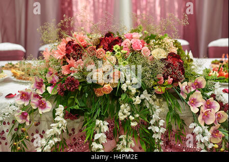 Beautiful white wedding arch decorated with pink and red flowers outdoors Stock Photo
