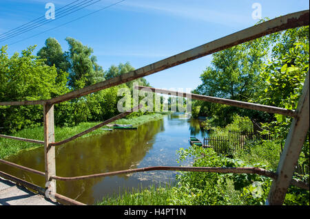 A channel of Narew river flowing through Pultusk, a historical town in Mazovia district of Poland. Damaged railing of a bridge. Stock Photo