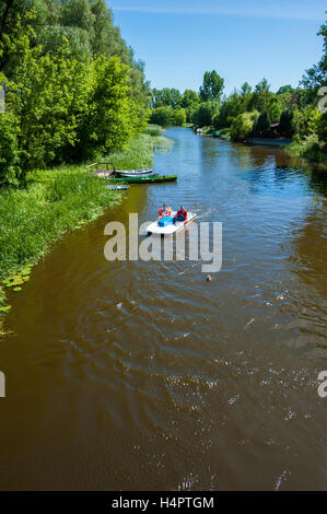 A channel of Narew river flowing through Pultusk, a historical town in Mazovia district of Poland. Vacationers on a paddle boat. Stock Photo