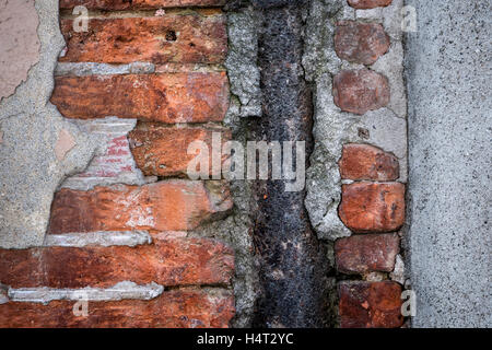 Antique wall with red old bricks, rusty metal and layers of plaster in Toulouse, France, closeup. Stock Photo