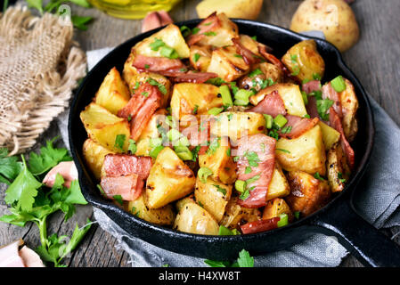 Fried roasted potatoes with bacon, onions in frying pan, close up view Stock Photo
