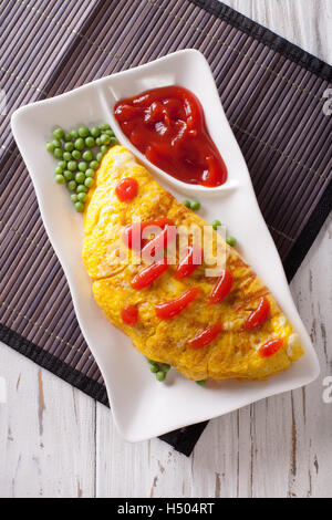 Japanese Omurice omelet stuffed with rice and chicken close-up on a plate. vertical top view Stock Photo