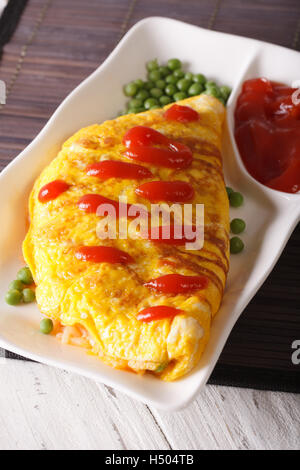 Japanese omelet stuffed with rice and chicken close-up on a plate. vertical Stock Photo