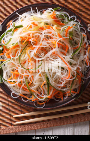 Chinese noodles with cucumber and carrot on a plate close-up. Vertical top view Stock Photo