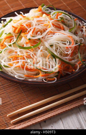 Chinese noodles with cucumber and carrot on a plate close-up. Vertical Stock Photo