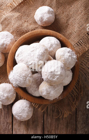 Mexican wedding cookies close up in a wooden bowl on the table. vertical top view Stock Photo