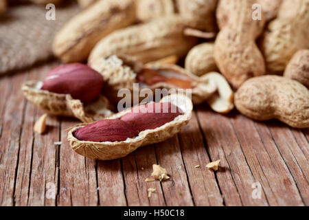 closeup of a pile of peanuts in its shells, on a rustic wooden surface Stock Photo