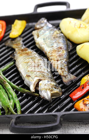 grilled whole rainbow trout with vegetables on grill pan Stock Photo