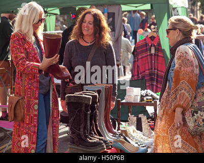 At a clothes stall in the North Laine area of Brighton a shopper thinks about buying a pair of boots Stock Photo