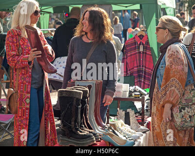 At a clothes stall in the North Laine area of Brighton a shopper thinks about buying a pair of boots Stock Photo