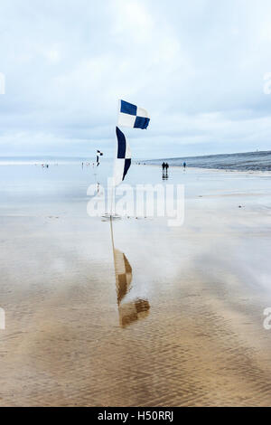 Black and white check marker flags on the windswept beach at Westward Ho!, Devon, England, UK Stock Photo