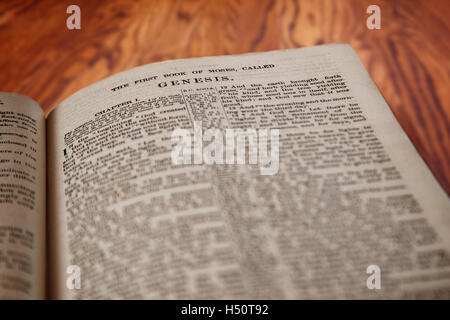 Closeup of an old Holy Bible opened to the famous Book of Genesis on a rustic wooden table. Deliberate focus on the title. Stock Photo