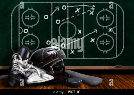 Ice hockey equipment consisting of skates, helmet, stick and puck with background play strategy drawn on chalk board with copy s Stock Photo