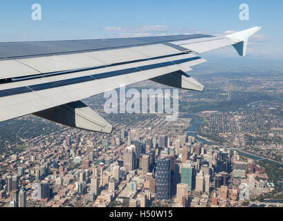 Airplane window view showing wing of the plane flying over downtown Calgary with its landmark Calgary Tower. Stock Photo