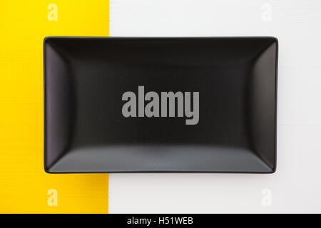 Empty black ceramic dish on over white and yelloe  wooden table, rectangle dish Stock Photo