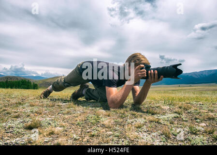 Close-up portrait photographer lying on the grass in mountains Stock Photo
