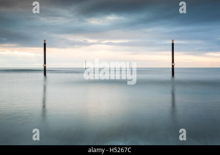 Navigation guide posts out at sea in the North Sea off the Northumberland coast, long exposure on an overcast day Stock Photo