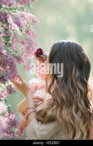 Mother holding baby girl with a flower wreath on her head. Stock Photo